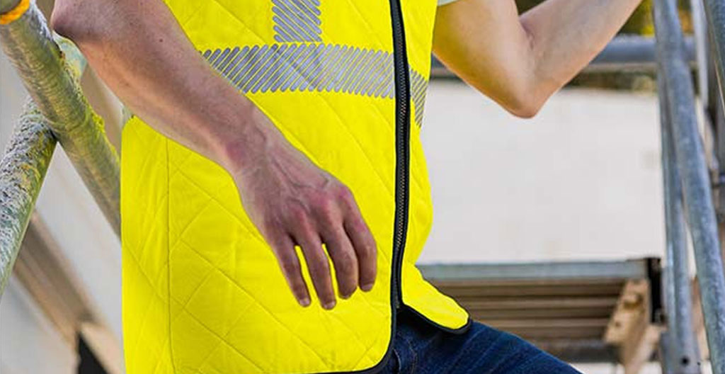 Professionnel vu de dos ajustant son gilet technique dans un vestiaire moderne, geste naturel de préparation avant intervention, lumière naturelle latérale